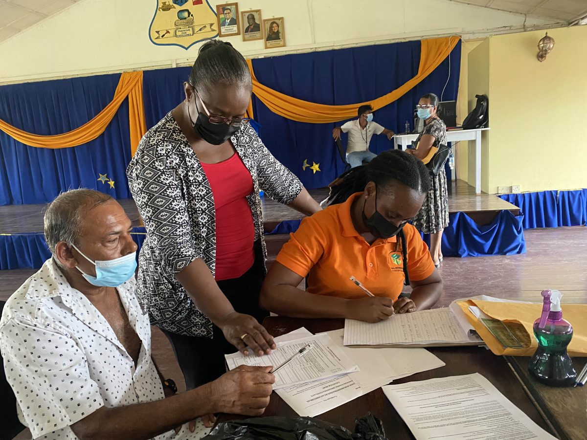 Acting SBB Chief Executive Officer Vanessa Thompson (standing) helping an SBB client to fill his forms