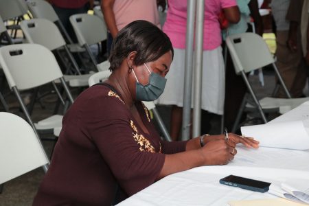 A beneficiary of the programme signs her home improvement contract (CH&PA photo)
