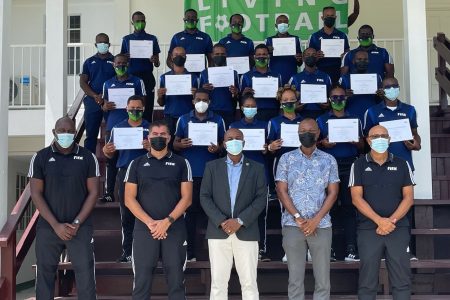 GFF President Wayne Forde (centre) flanked by the FIFA instructors, as the participants display their certificates of participation following the conclusion of the FIFA Member Association Refereeing Course on Friday at the National Training Centre