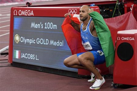 Lamont Marcell Jacobs, of Italy, celebrates by the clock after winning the final of the men's 100-metre at the 2020 Summer Olympics, on Sunday, August 1, 2021, in Tokyo. AP/P
