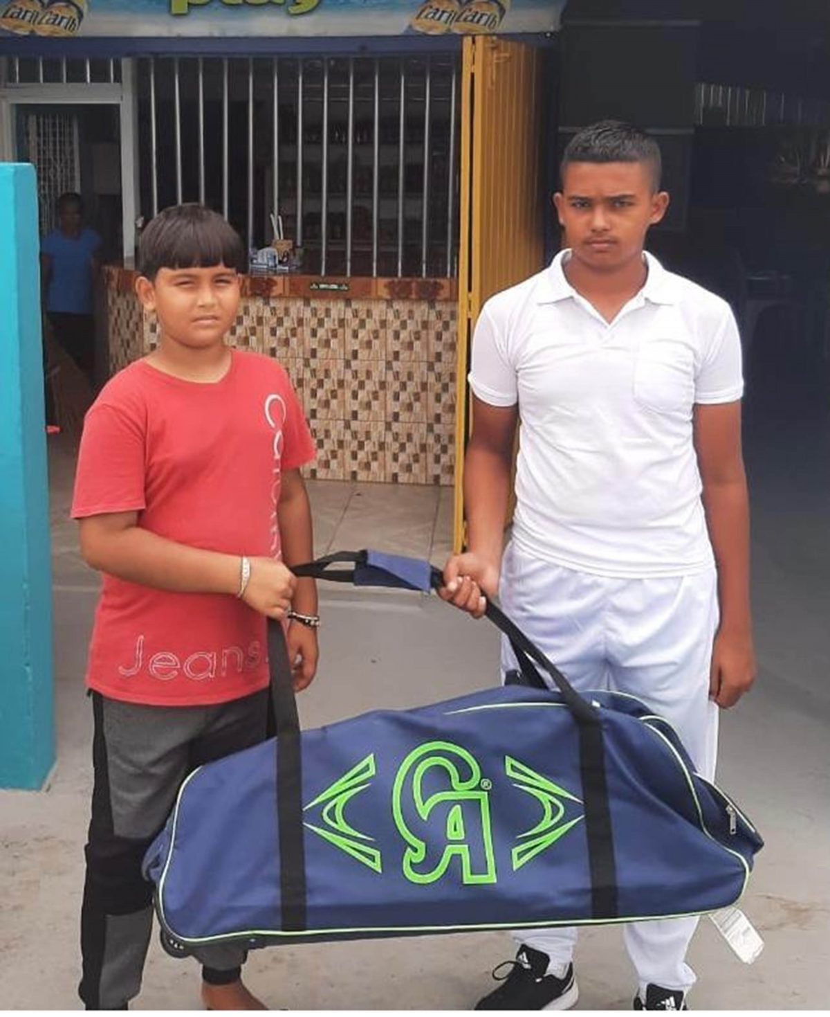 Lakeram Singh, right received the gear bag from his fellow young cricketer Akash Sheriff who represented the organizers