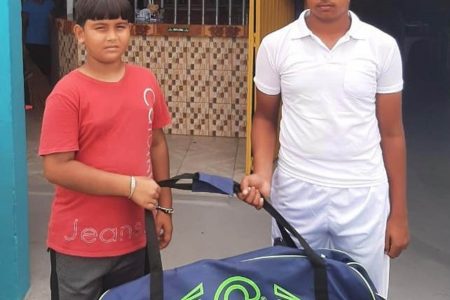 Lakeram Singh, right received the gear bag from his fellow young cricketer Akash Sheriff who represented the organizers