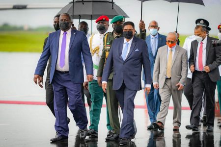 Prime Minister Mark Phillips (left) escorting President of the Republic of Suriname, Chandrikapersad Santokhi (second from left) yesterday at CJIA (Department of Public Information photo)