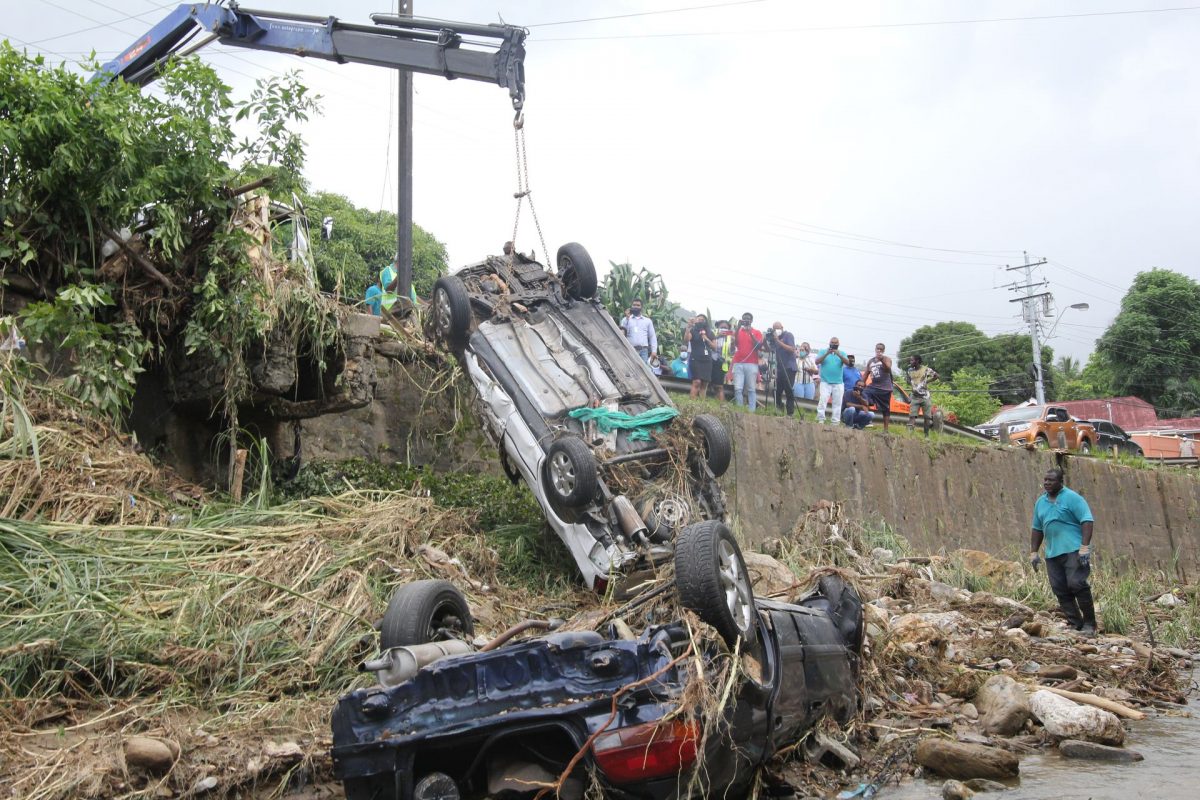 A Hiab crane lifts one of two vehicles out of the St Ann’s River yesterday. The vehicles were washed into the river during Tuesday’s floods which affected various communities.