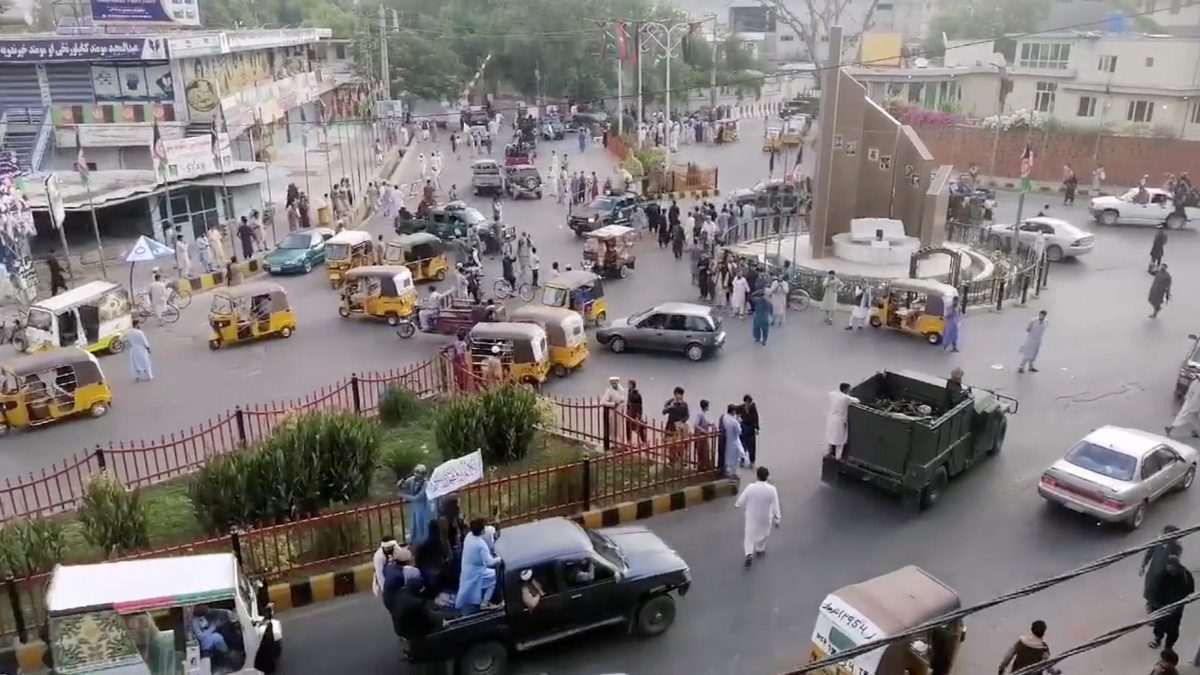 Taliban militants waving a Taliban flag on the back of a pickup truck drive past a crowded street at Pashtunistan Square area in Jalalabad, Afghanistan in this still image taken from social media video uploaded on August 15, 2021. Social media website/via REUTERS