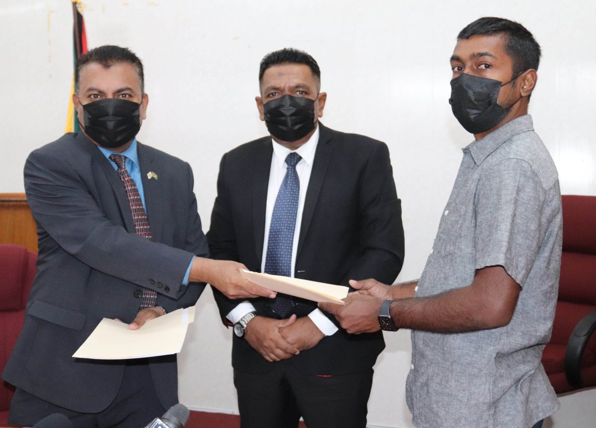 Managing Director of Umami Inc, Chris Persaud (right) and Chief Executive Officer of GO-Invest, Dr Peter Ramsaroop exchanging the signed documents. At centre is Minister of Agriculture Zulfikar Mustapha. (Ministry of Agriculture photo)
