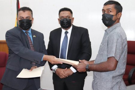 Managing Director of Umami Inc, Chris Persaud (right) and Chief Executive Officer of GO-Invest, Dr Peter Ramsaroop exchanging the signed documents. At centre is Minister of Agriculture Zulfikar Mustapha. (Ministry of Agriculture photo)