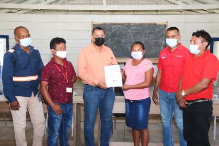 Minister of Housing and Water, Collin Croal (third from left), hands over the contract for the well at Jawalla to Toshao  Verrom Henry, as Hinterland Services Director,  Ramchand Jailall (2nd from right) and other village councillors watch on. (CH&PA photo)