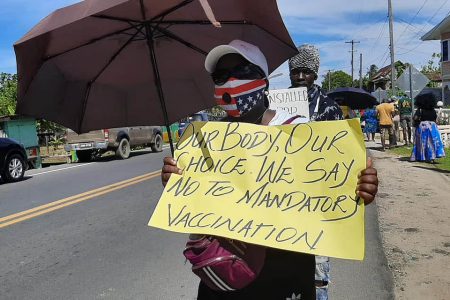 A protestor with her placard yesterday during the protest at Victoria, East Coast Demerara (APNUAFC photo)