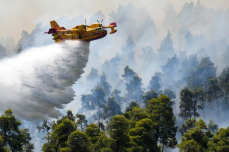 A firefighting airplane makes a water drop as a wildfire burns near the village of Ellinika, on the island of Evia, Greece, August 8, 2021. (Reuters photo)