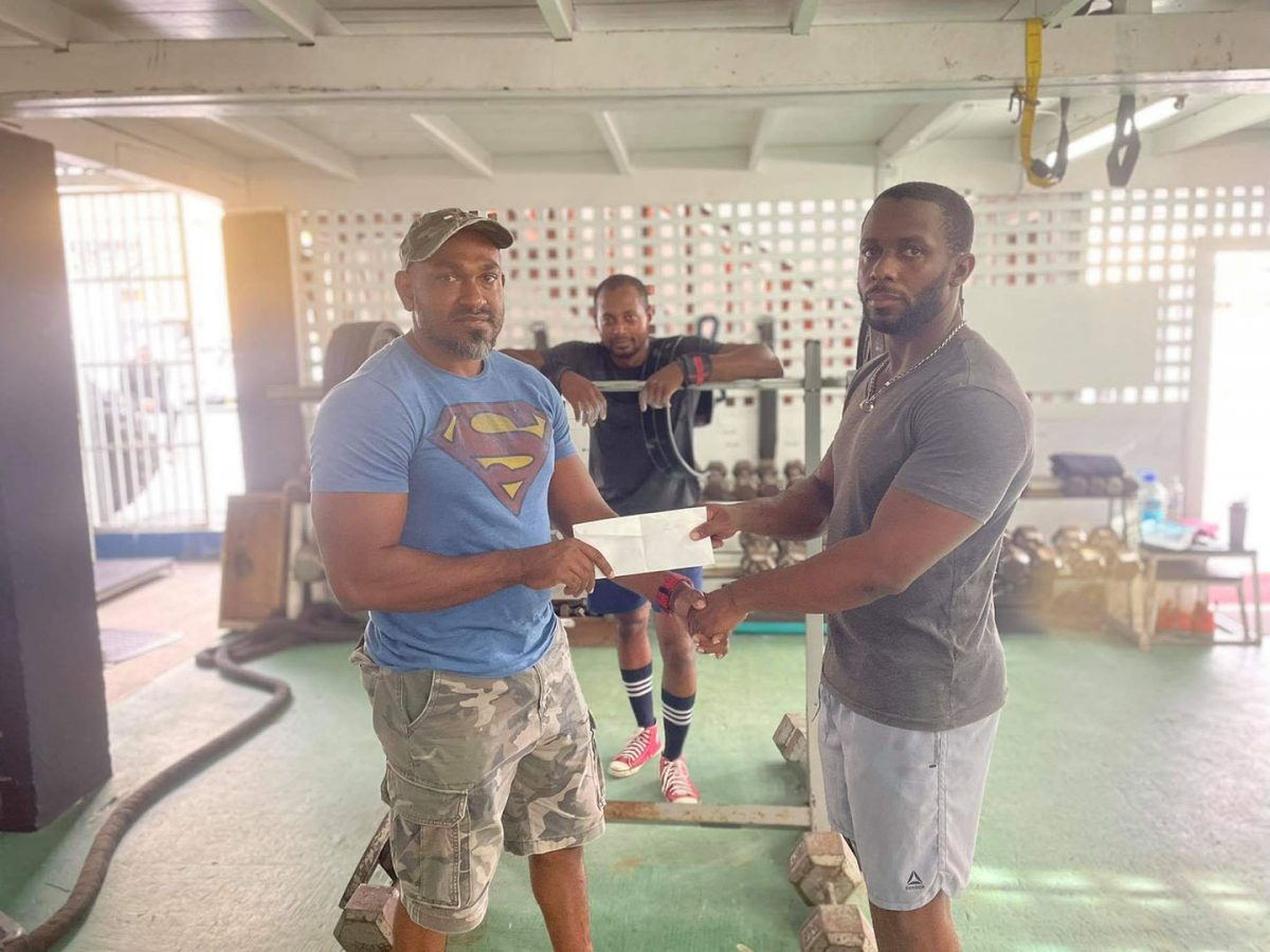 Paul Adams (left) of Southern Imports Incorporated presents the sponsorship cheque to Wazim Mohammed in the presence of the latter’s training partner Matthew Maycock at the Flex Gym in Thomas Street, Kitty.