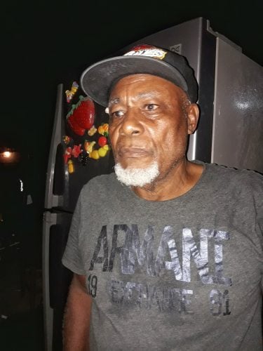 Landlord, Rudolph Gravesande standing in front of the refrigerator he rescued from the fire 