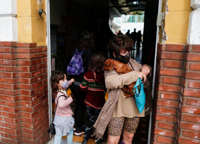 A woman carrying her dog leaves a polling station after casting her vote during primary legislative elections, in Buenos Aires, Argentina September 12, 2021. REUTERS/Agustin Marcarian