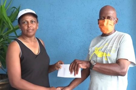 Widow of the late Wilbert Benjamin, Evette Benjamin, (left), hands over the sponsorship cheque to president and coach of the Flying Ace Cycle Club, Randolph Roberts.