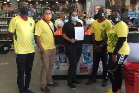 Freshco Supermarket Branch Manager Elizabeth Singh (centre) displays the letter of commitment in the presence of the EBFA ATC Coaches.
