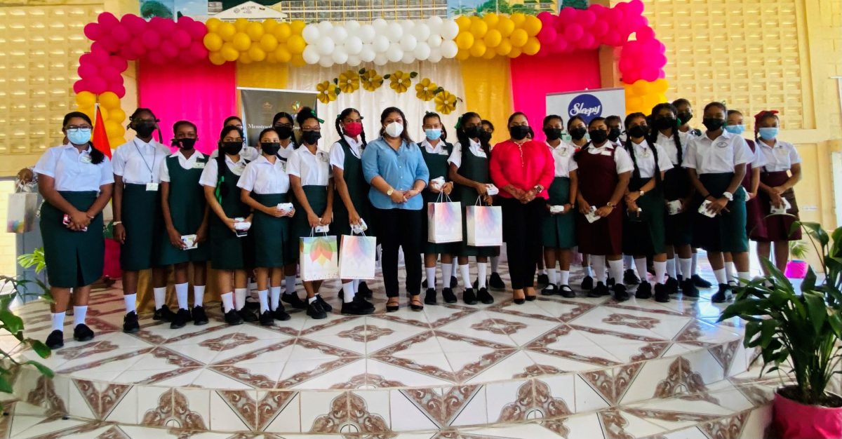 First Lady Arya Ali along with Minister of Education Priya Manickchand standing with students of secondary schools who received sanitary products.
