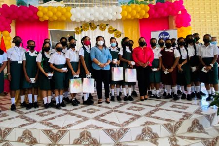 First Lady Arya Ali along with Minister of Education Priya Manickchand standing with students of secondary schools who received sanitary products.