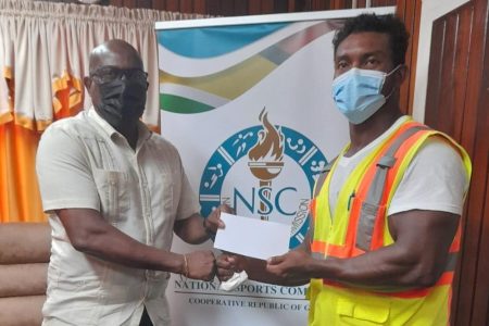 Director of Sport, Steve Ninvalle (left) presents the sponsorship cheque to Carlos Peterson-Griffith towards his participation at the 2021 World Classic Powerlifting Championships in Halmstad, Sweden.