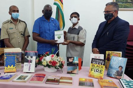 Minister of Home Affairs, Robeson Benn (second from left) handed over the books to Chairman of the National Library, Petamber Persaud (second from right) yesterday at the National Library