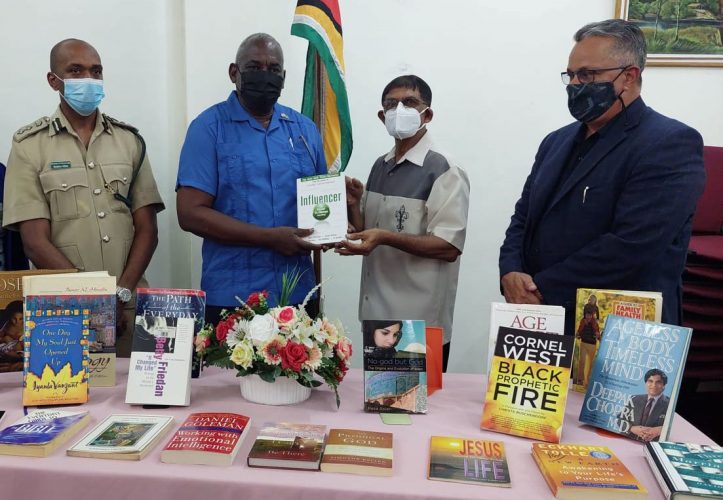 Minister of Home Affairs, Robeson Benn (second from left) handed over the books to Chairman of the National Library, Petamber Persaud (second from right) yesterday at the National Library