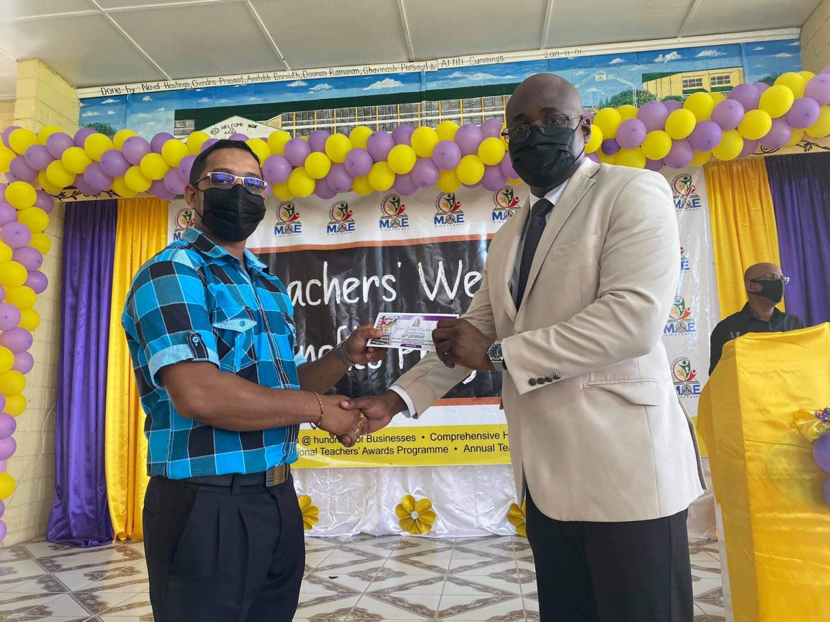 Education Specialist Dr. Olato Sam (right) handing over one of the welfare benefits to a teacher of the Abram Zuil Secondary School, Parmanand Singh.