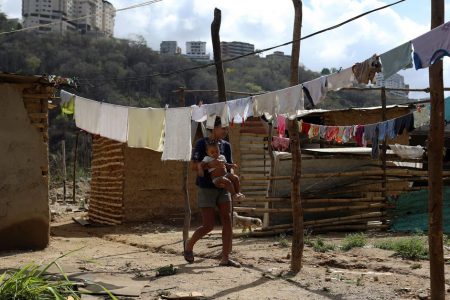 A woman walks across hanged clothes on a vacant lot where families are settling since they cannot afford to pay rent anymore, in the municipality of Sucre, near Caracas, Venezuela June 12, 2020. REUTERS/Manaure Quintero