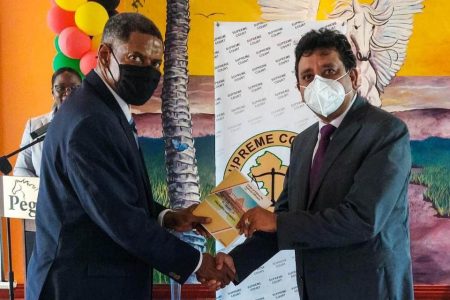 Justice Franklyn Holder (left) presenting a copy of the revised code of ethics  to Attorney General Anil Nandlall SC