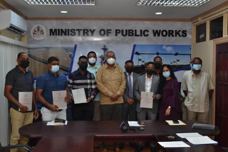 Ministers of Public Works Juan Edghill and Deodat Indar flanked by representatives of the firms that signed contracts for major road projects on Friday 