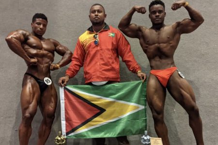 Guyana’s bodybuilders Darious Ramsammy, left, and Nicholas Albert, right, along with their manager Videsh Sookram,  display the Guyana flag after gold and silver medal performances at the Santo Domingo Open recently.