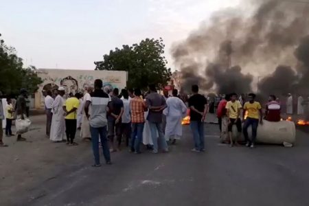 People gather around as smoke and fire are seen on the streets of Khartoum, Sudan, amid reports of a coup, October 25, 2021, in this still image from video obtained via social media. RASD SUDAN NETWORK via REUTERS