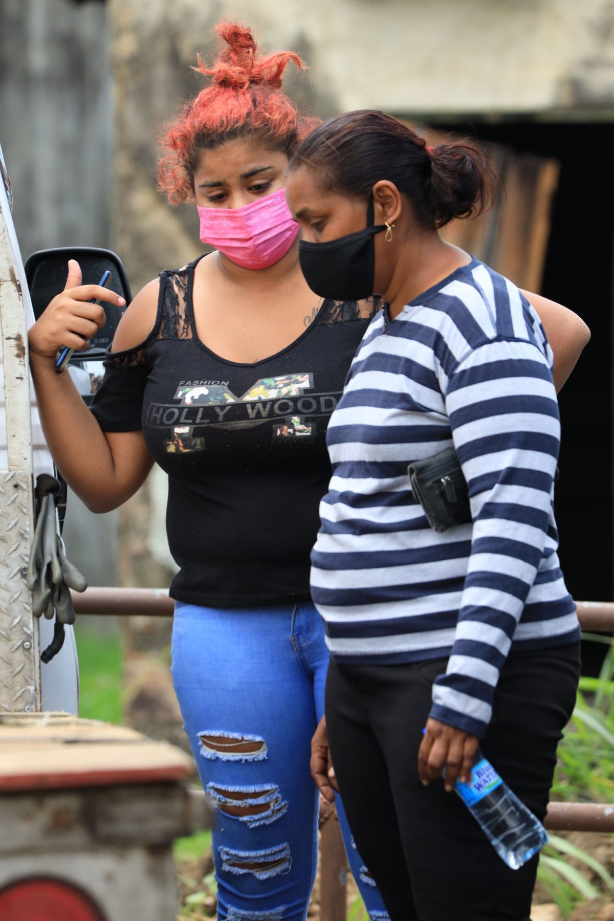 Nyron Philip’s common-law wife Sarah Basdeo, left, chats with Ritchie Ragoo’s common-law wife Fareeda Mohammed, as they wait to view the bodies at the Forensic Science Centre, St James, yesterday. Both men were shot in Carapo on Monday night.