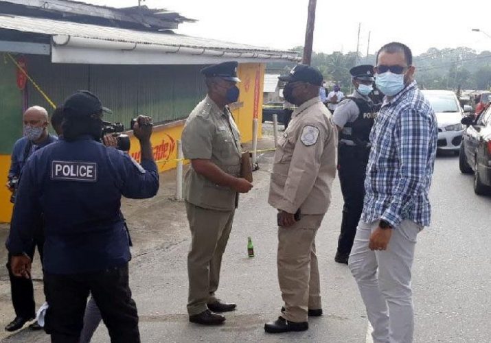 On the scene: Deputy Commissioner of Police, McDonald Jacob, centre right, speaks with a senior Eastern Division officer on the scene of yesterday’s murder/robbery along the Valencia Old Road and San Pablo Trace, Valencia.