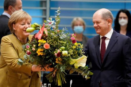 Acting German Chancellor Angela Merkel receives a bouquet from acting German Finance Minister Olaf Scholz prior to the weekly cabinet meeting at the Chancellery in Berlin, Germany, Nov 24, 2021. Markus Schreiber/Pool via REUTERS