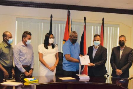 Home Affairs Minister Robeson Benn (fifth from left) hands over the contract document to Managing Director of Mohamed’s Enterprise Nazar Mohamed. (Ministry of Home Affairs photo)