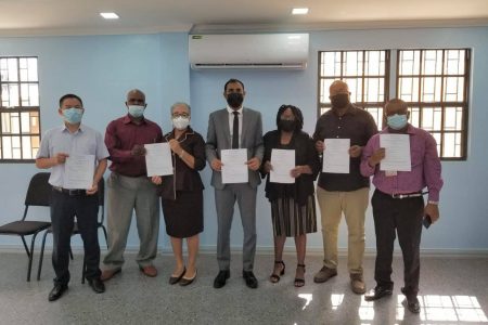 NACCIE representatives and members of BOSAI’s management along with Chief Labour Officer Dhaneshwar Deonarine (at centre) hold signed copies of the resolutions from the meeting.  (Ministry of Labour Photo)