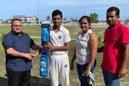 Alvin Mohabir (second from left) receives the bat from GCB president, Bissoondyal Singh in the presence of Mohabir’s parents.