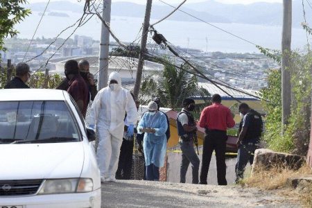 Police officers and crime scene investigators gather on the scene of a triple murder in Desperly Crescent, Laventille yesterday.