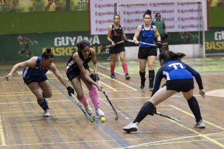 GCC Ignite’s Sarah Klautky (centre) being challenged by Vanessa Pires of Spartans during their clash in the ExxonMobil National Indoor Hockey Championships at the Cliff Anderson Sports Hall, Homestretch Avenue.