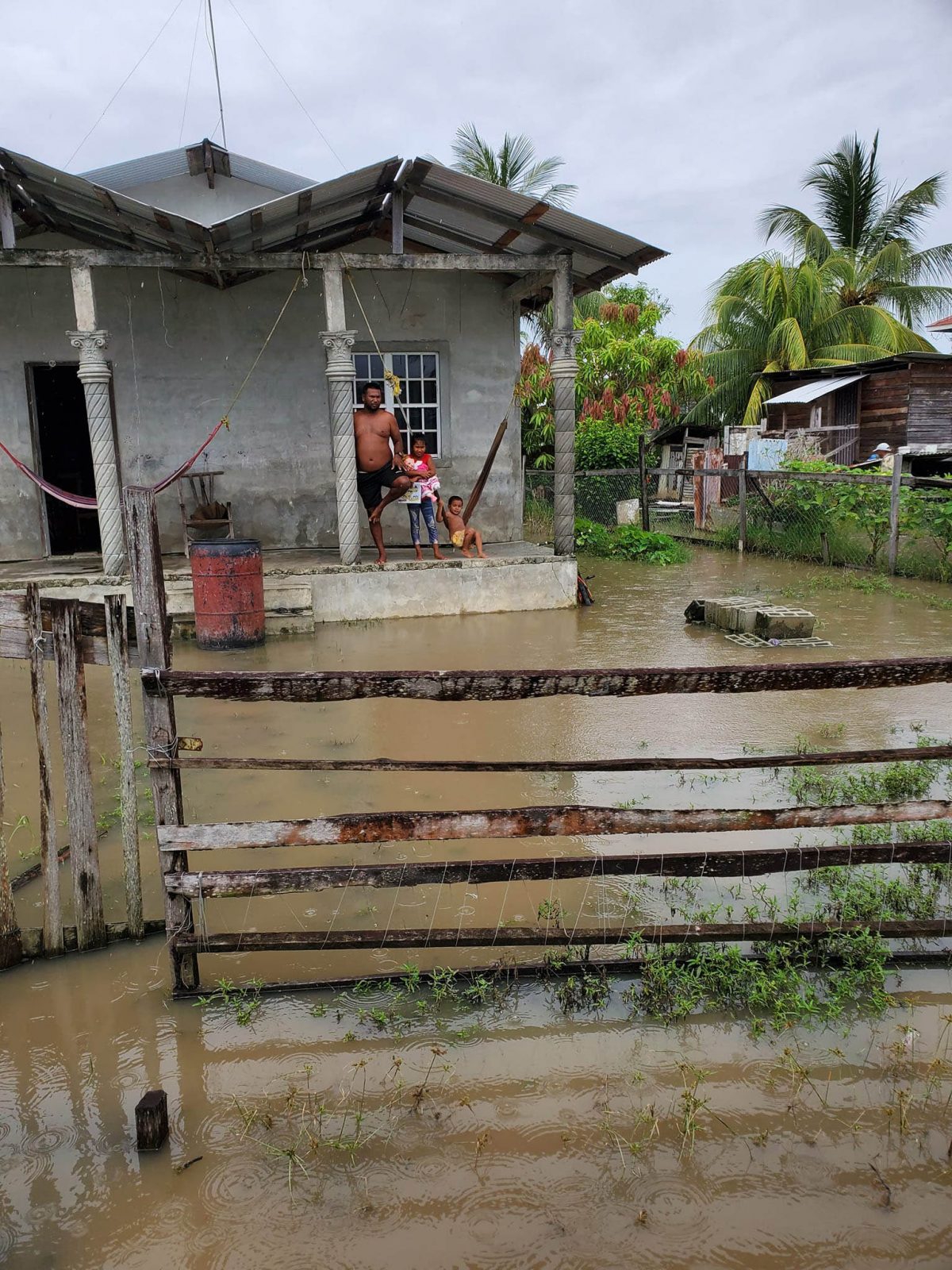 A father and his children looks out at their flooded yard in Tuschen Phase 3. The area was visited by Minister Deodat Indar (Photo Courtesy of Minister of Public Works Deodat Indar)