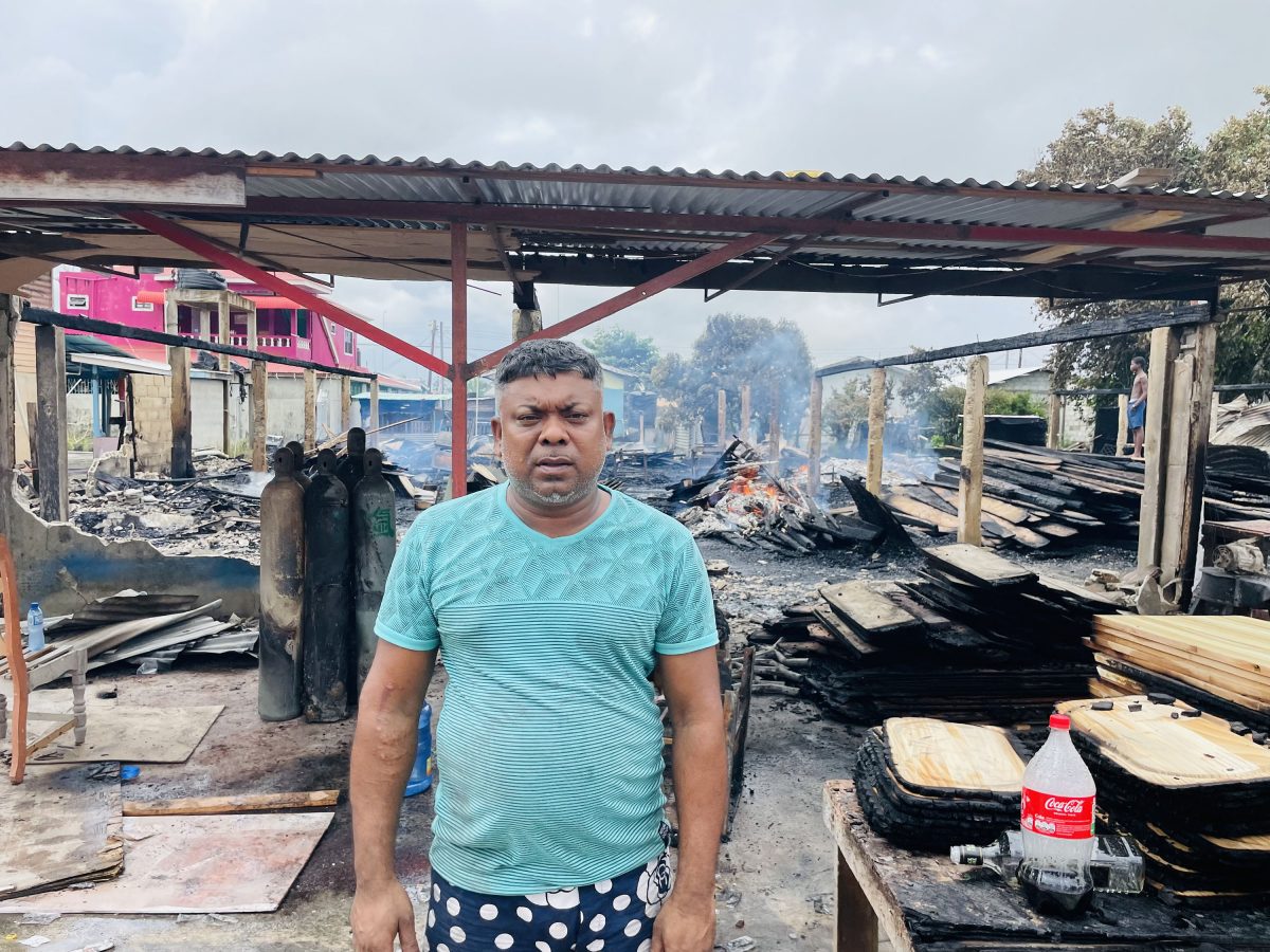 The distressed Navindra Persaud standing in front of the burnt building 