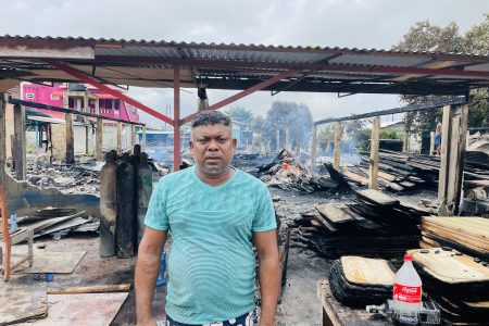 The distressed Navindra Persaud standing in front of the burnt building 