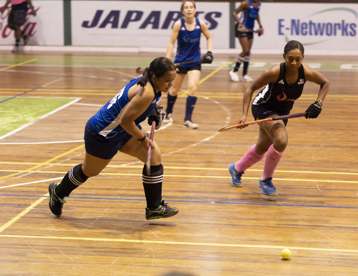 GCC Roulette’s Kirsten Gomes (blue) trying to evade the pursuit of GCC Ignite captain Aliyah Gordon at the Cliff Anderson Sports Hall in the ExxonMobil National Indoor Championship