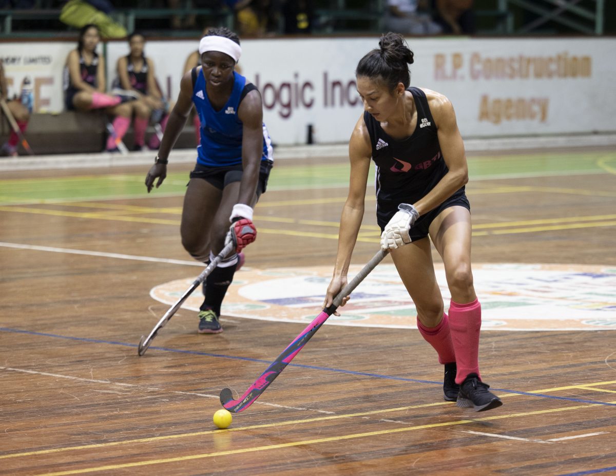 Samantha Fernandes of GCC Spartans on the attack while being pursued by Shebiki Baptiste of GCC Roulettes in the ExxonMobil National Indoor Hockey Championship at the Cliff Anderson Sports Hall, Homestretch Avenue.