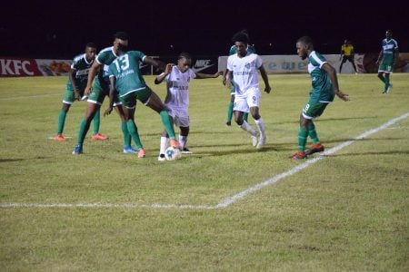 Darren Niles (centre) of Santos challenging Den Amstel’s Rondel Hudson for possession in the presence of several teammates 