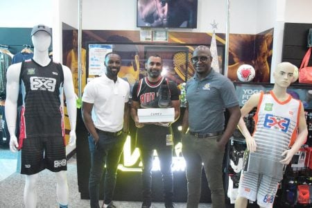 Managing Director of MVP Sports Ian Ramdeo (centre), tournament coordinator Rawle Toney (right) and Compton Babb displaying the Steph Curry sneakers that would be up for grabs at the three-point shootout tomorrow. The team uniforms are also on display