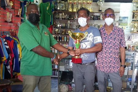 Rugby Manager George David, collects one of the trophies from Victor Sunich of Trophy Stall (Canada) in the presence of Ramesh Sunich at the South Road location.