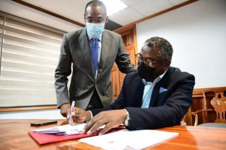 Kavan Gayle President General of the Bustamante Industrial Trade Union signs an one-year wage agreement in the presence of Finance Minister Dr Ni