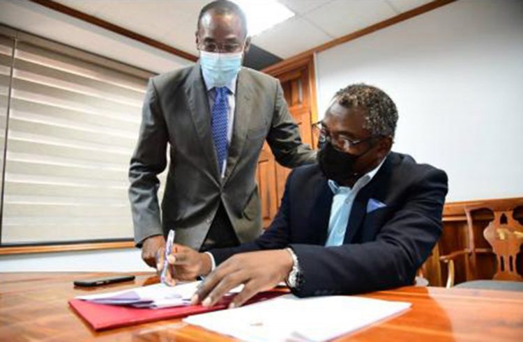 Kavan Gayle President General of the Bustamante Industrial Trade Union signs an one-year wage agreement in the presence of Finance Minister Dr Ni