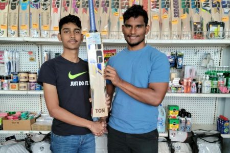 Manager of Cricket Equipment Guyana, Ajay Gainda (left) presents Aaron Beharry with his new bat.