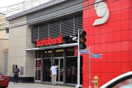 A member of the public waits to go into Scotiabank branch at the corner of Park and Pembroke Street, Port-of-Spain.